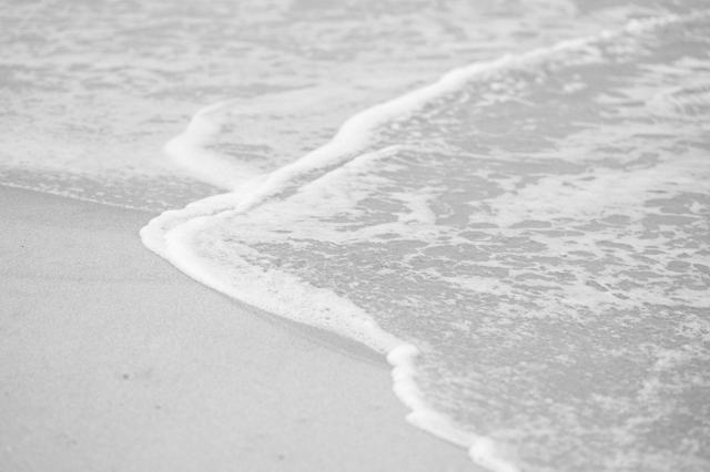 A wave sliding up the sand, black and white