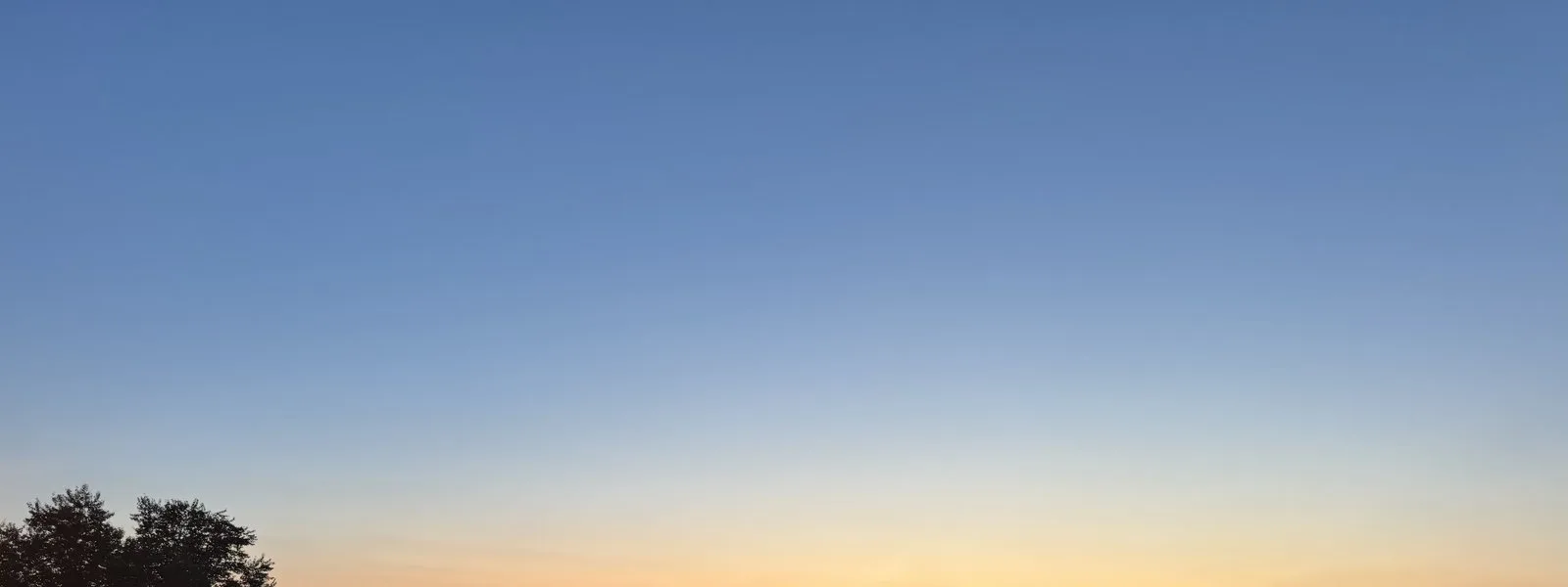 Dusk over a valley city, an orange band of light along the horizon